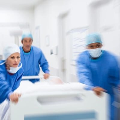 Three doctors in blue gowns and surgical masks